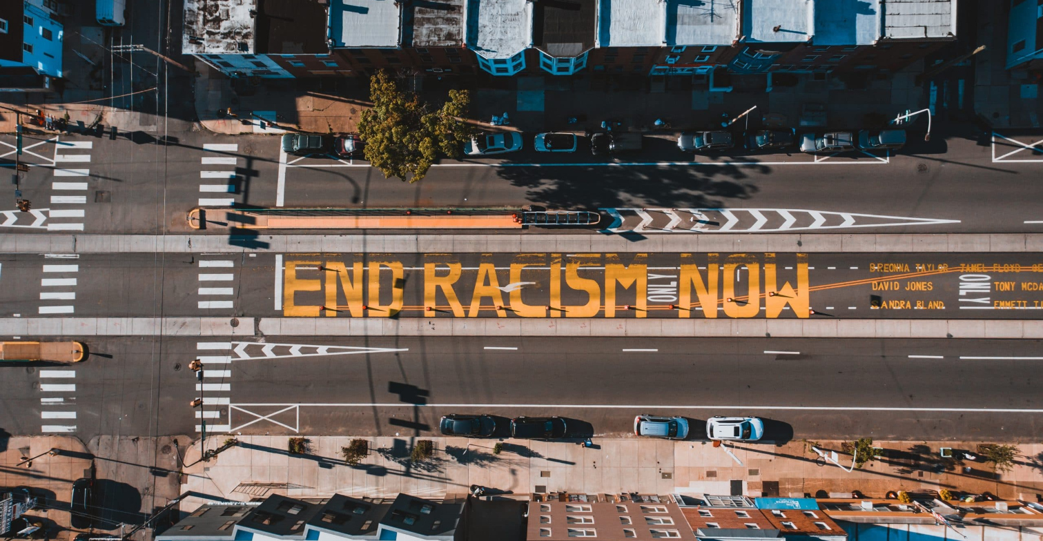 Das Foto einer Straße aus der Vogelperspektive, auf der Straße steht 'End Racism Now'.
