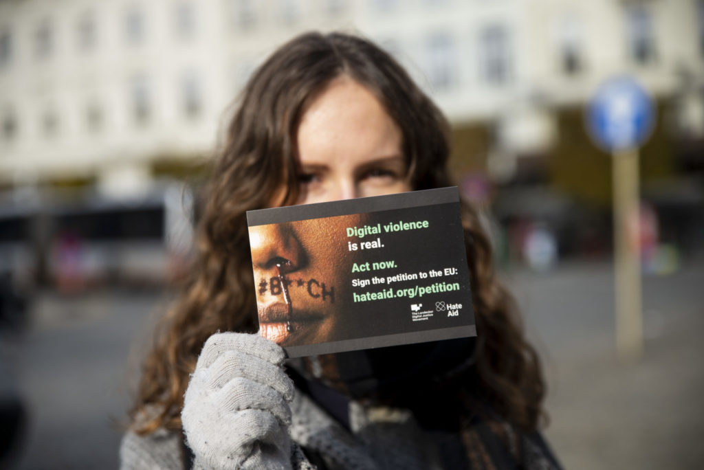 Eine Frau bei der Protestveranstaltung mit einer Postkarte in der Hand.