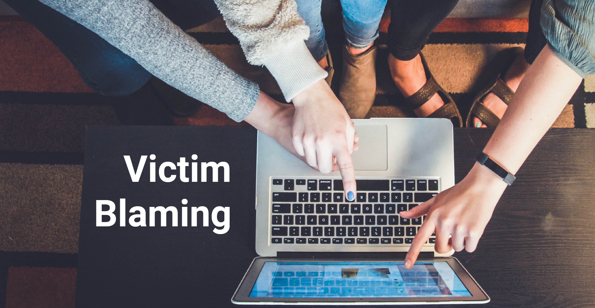 Ein Laptop, an dem zwei Menschen sitzen und auf den Bildschirm zeigen. Dazu der Text: Victim Blaming.