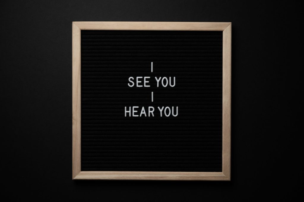 Eine Stecktafel, auf der die Worte "I see you / I hear you" abgebildet sind.