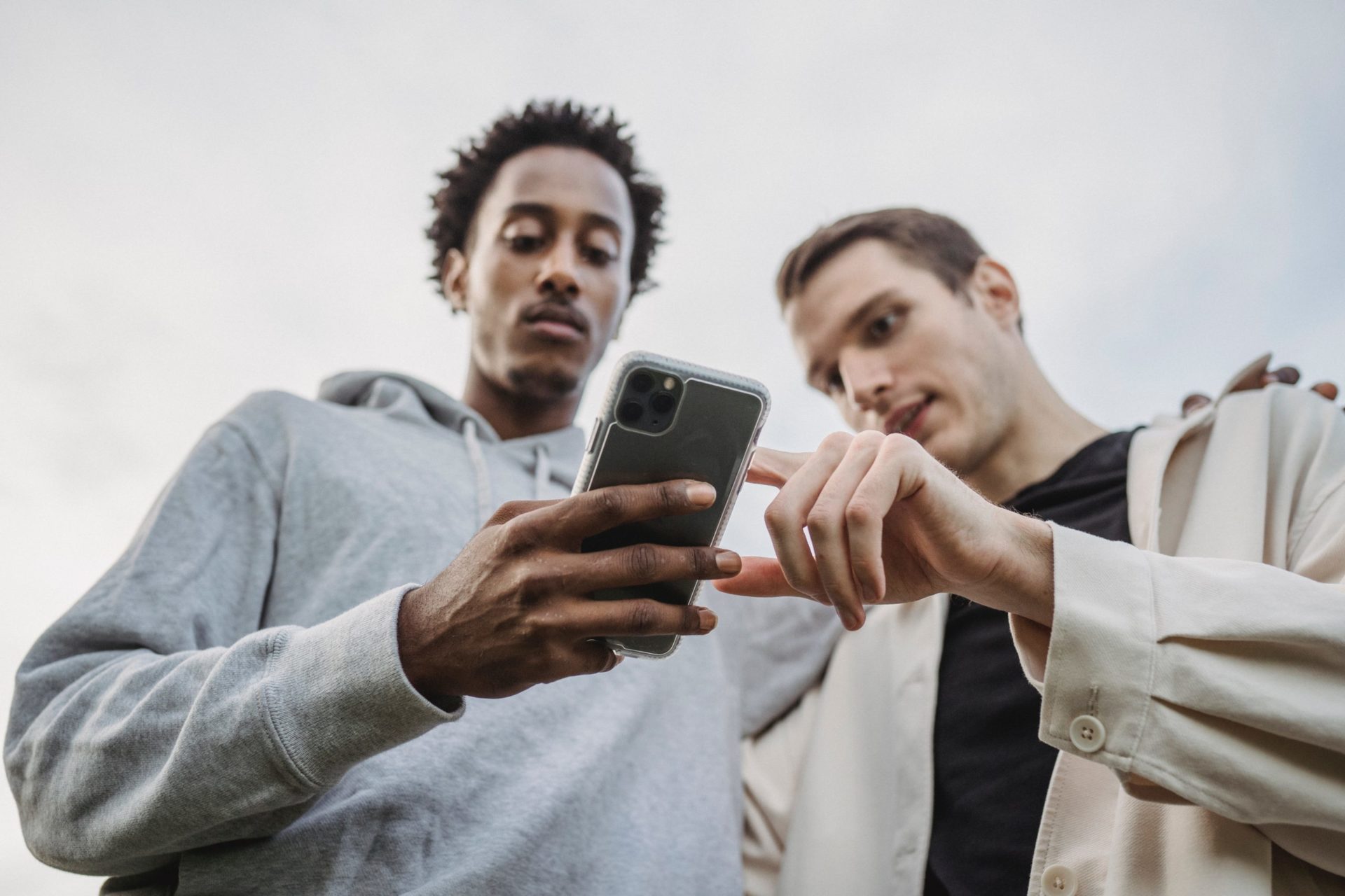 Zwei junge Männer, die gemeinsam auf ein Smartphone schauen.