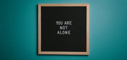 Eine Stecktafel, auf der die Worte "You are not alone" abgebildet sind.