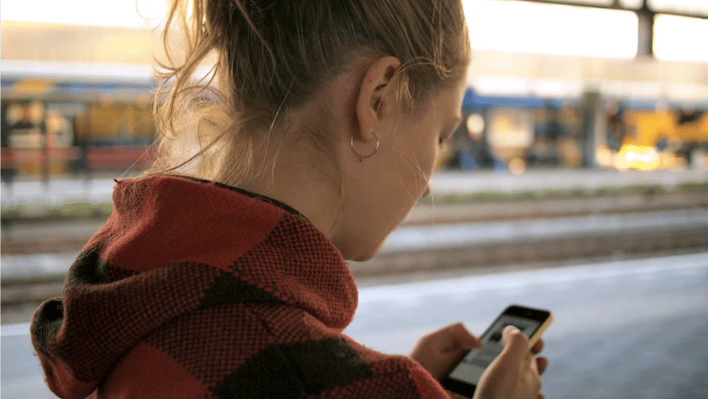 Eine Frau sieht auf ihr Handy - Smartphone-Sicherheit Tipps