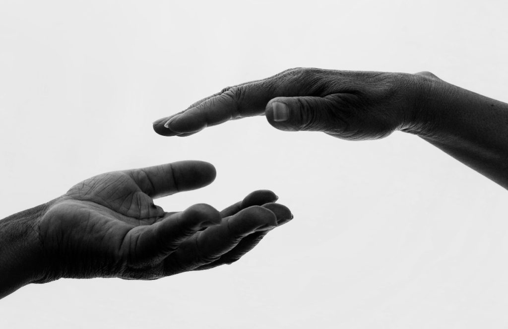 Ein monochromes Foto zweier Hände, die sich fast berühren.
