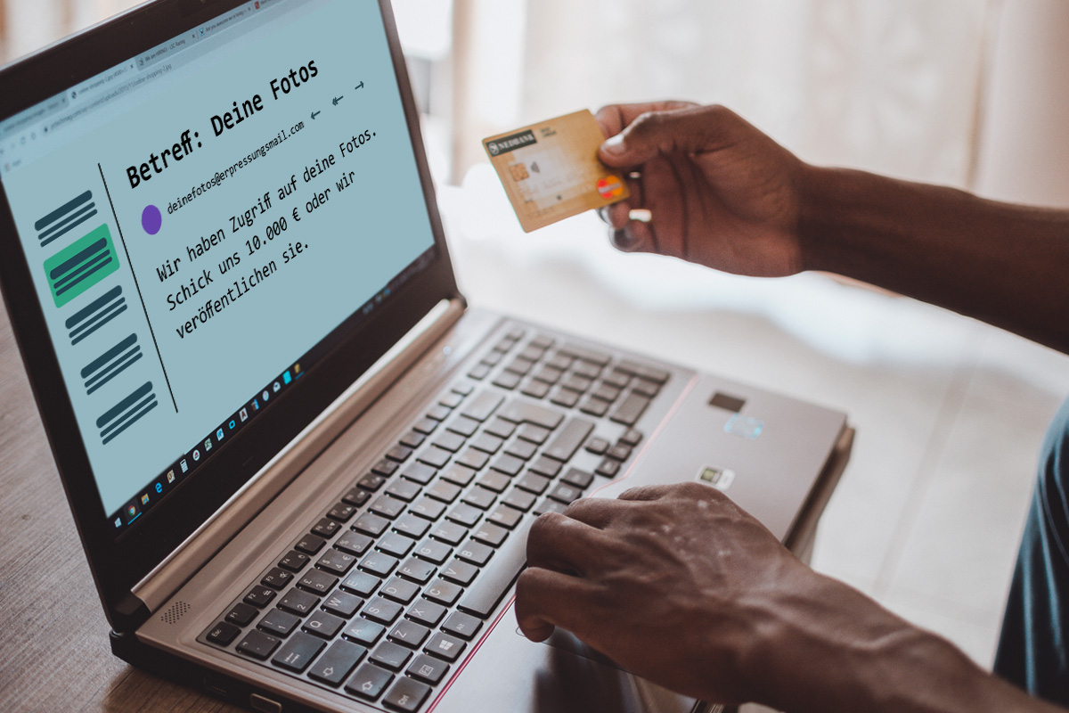 Person hält Kreditkarte in der Hand, während sie vor ihrem Computer sitz, welcher eine Erpressungsnachricht zeigt.