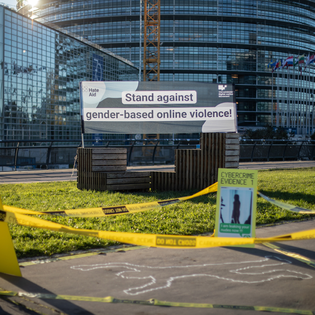 A sign in front of the European Parliament in Strasbourg with the slogan "stand against gender-based online violence!" and a reenacted crime scene in front of it