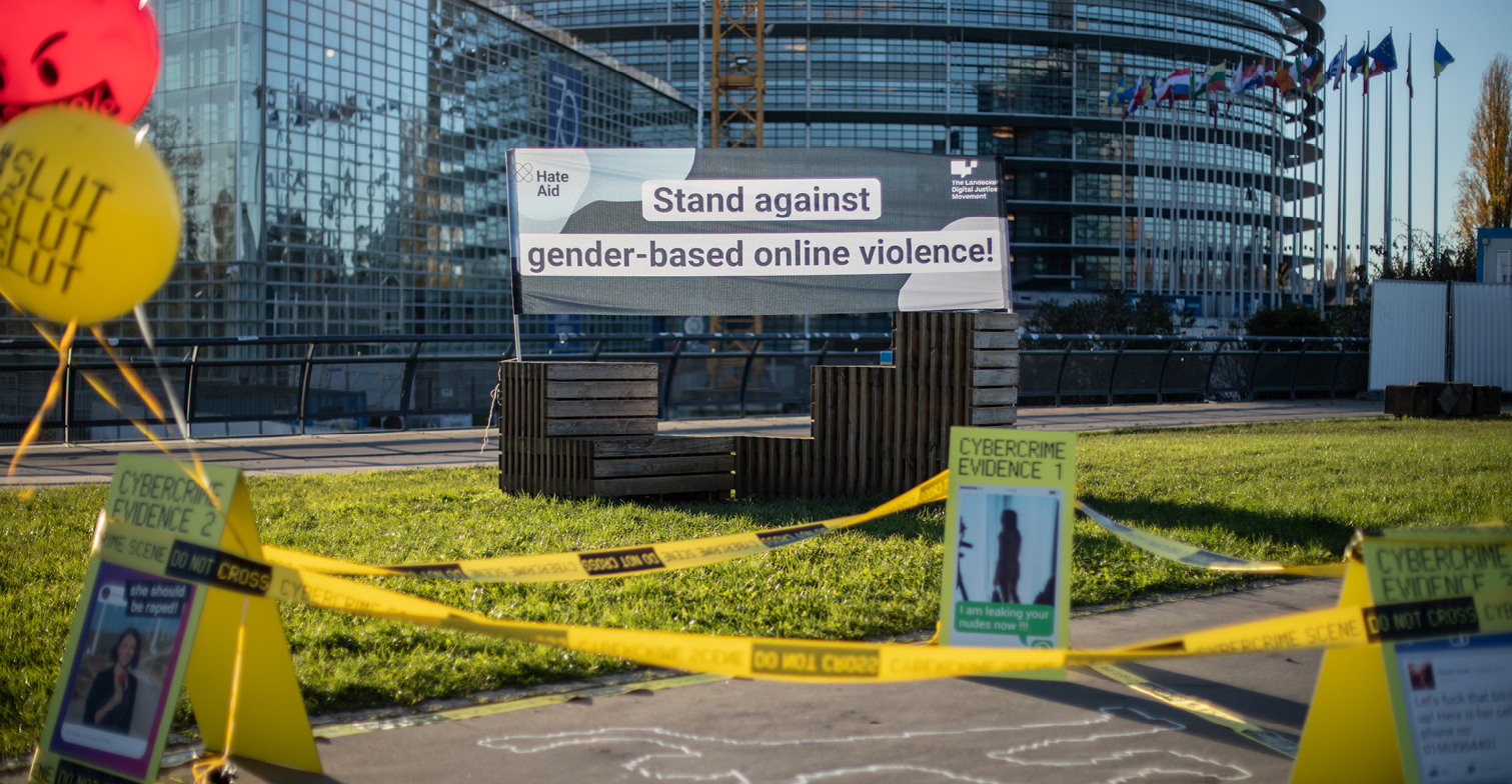 A sign in front of the European Parliament in Strasbourg with the slogan "stand against gender-based online violence!" and a reenacted crime scene in front of it