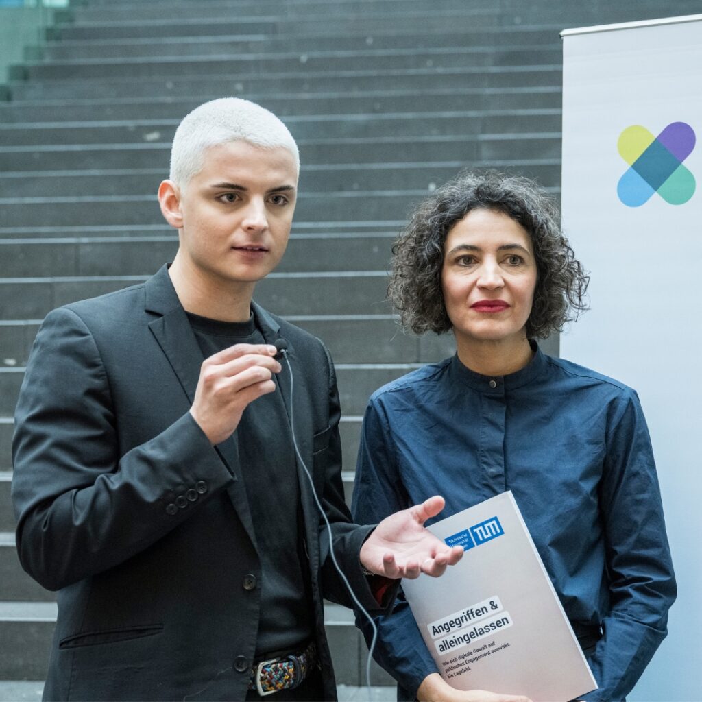 Das Foto zeigt Fabian Grischkat, der ein kleines Mikrofon hält. Neben ihm steht Anna-Lena von Hodenberg, die die Studie „Angegriffen & alleingelassen" in der Hand hält.